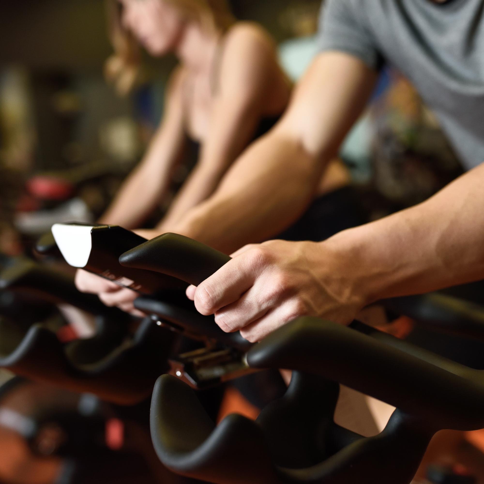 Close-up,Of,Hands,Of,A,Man,Biking,In,The,Gym, Close-up of hands of a man biking in the gym, exercising legs doing cardio workout cycling bikes. Couple in a spinning class wearing sportswear.