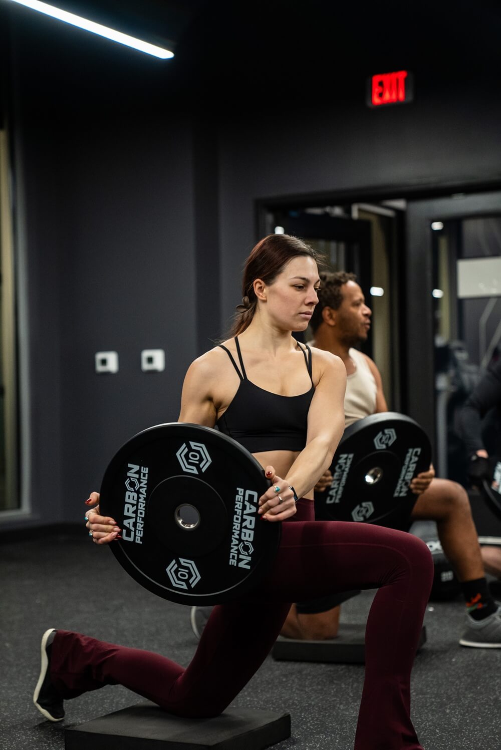 Edge Class with Weights A woman working out with a Carbon Performance weight plate