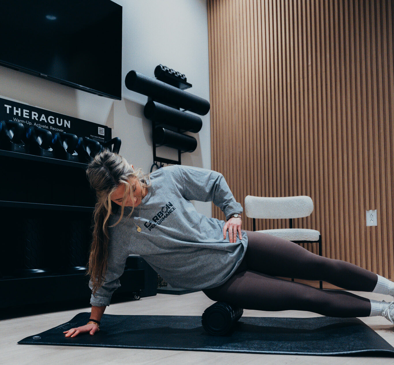 A woman using a foam roller with Carbon Performance's recovery amenities.