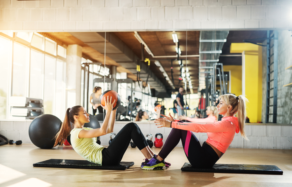 friends working out together performing medicine ball pass for core strength training