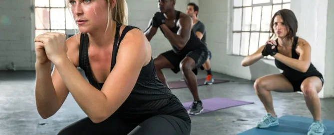 group of young adults working out together doing squats at a fitness center in nashville tn