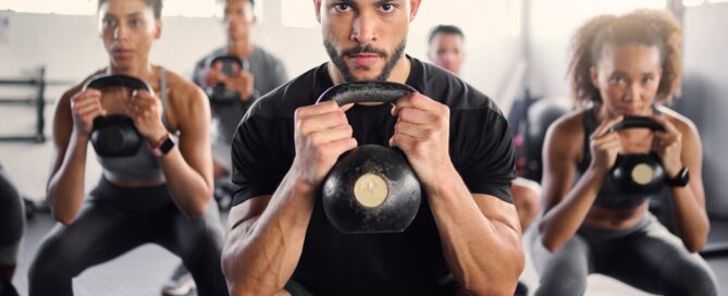 diverse group of people at a fitness class holding a kettlebell in the squat position