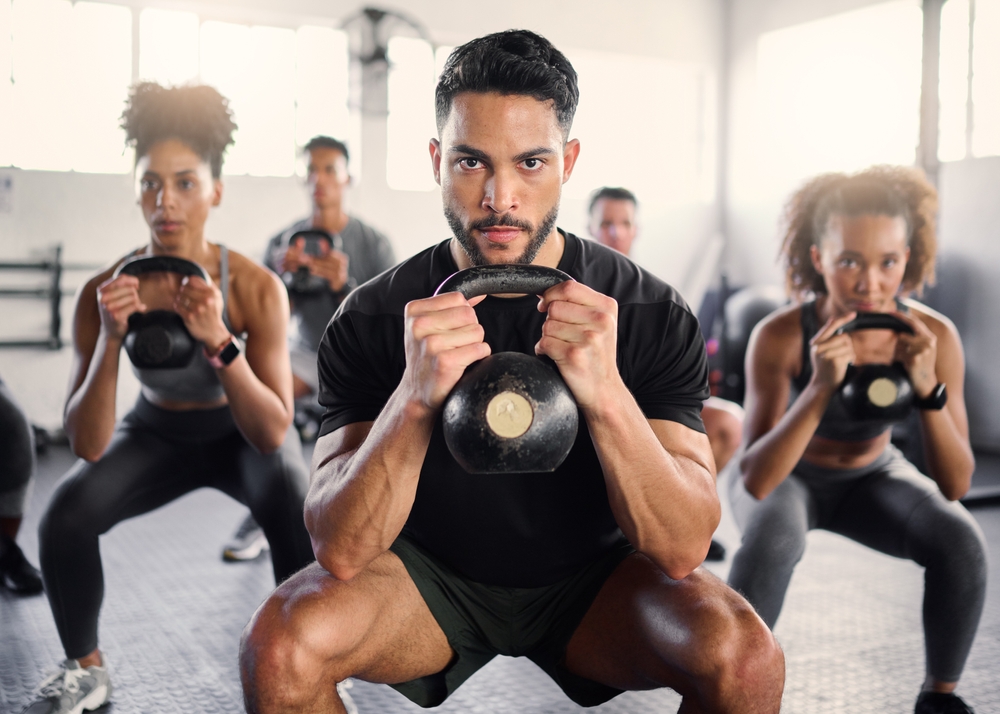 diverse group of people at a fitness class holding a kettlebell in the squat position