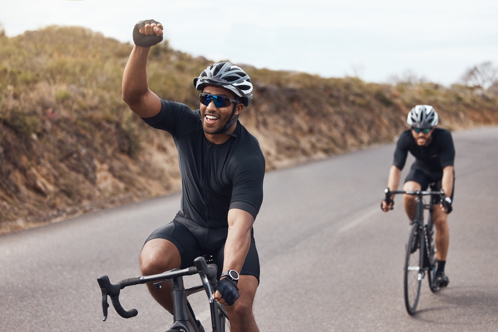 two men cycling outside on the road wearing helmets