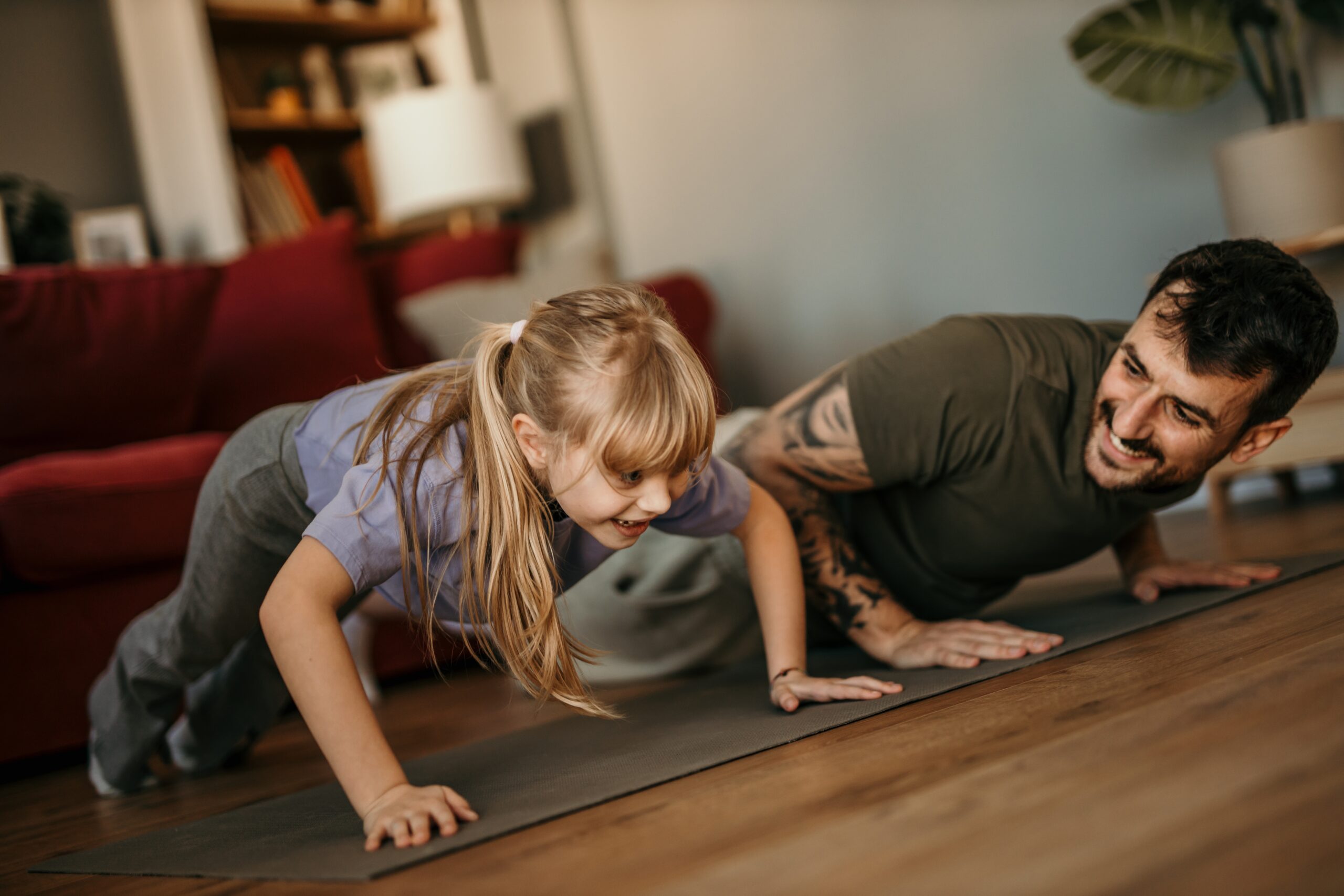 Father and daughter doung push ups in living room.