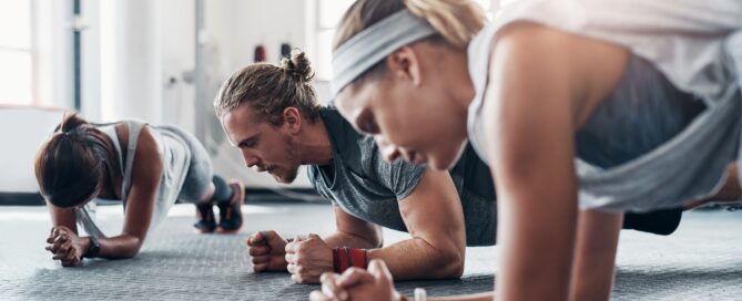 Group of gym goers all holding a plank.