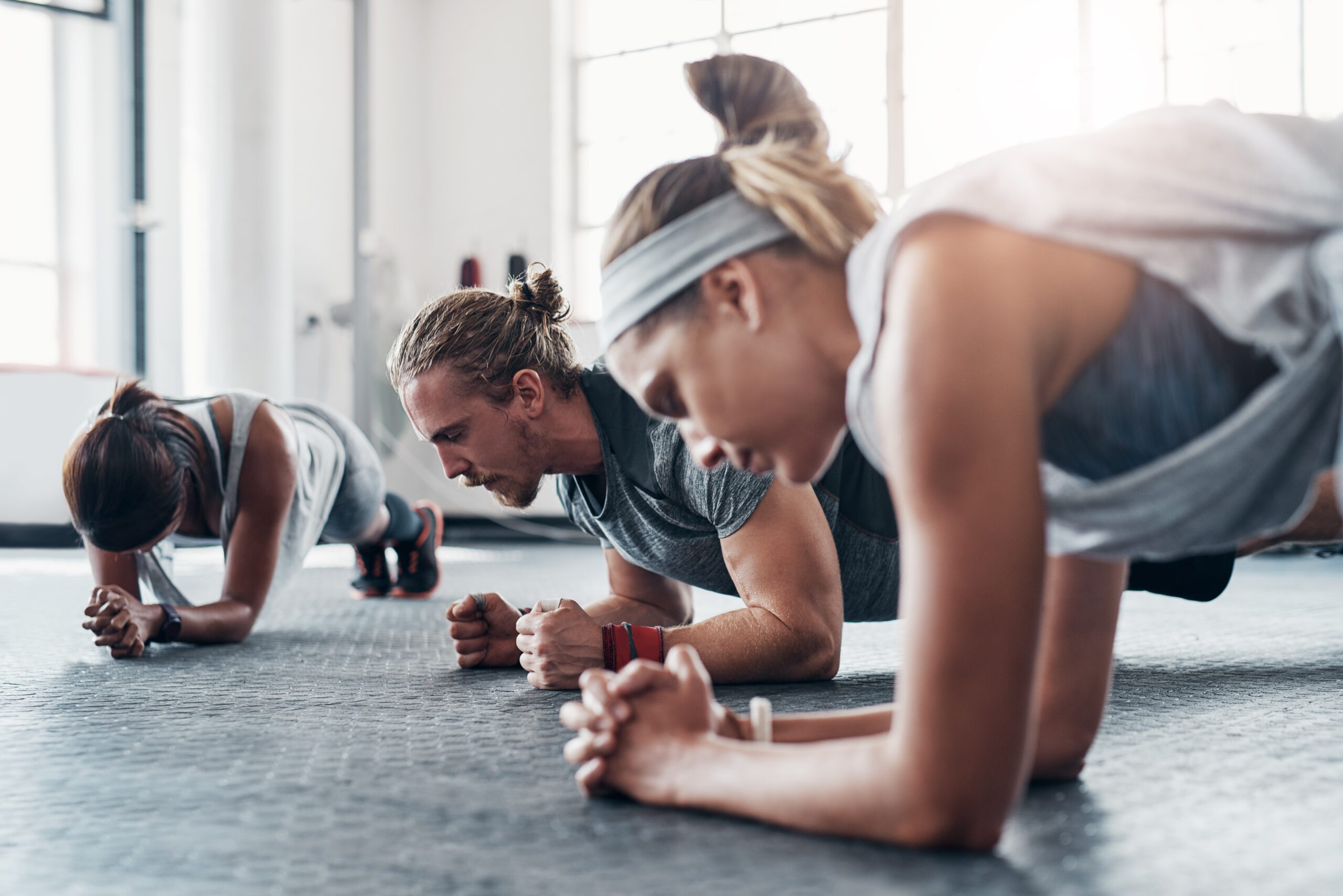 Group of gym goers all holding a plank.