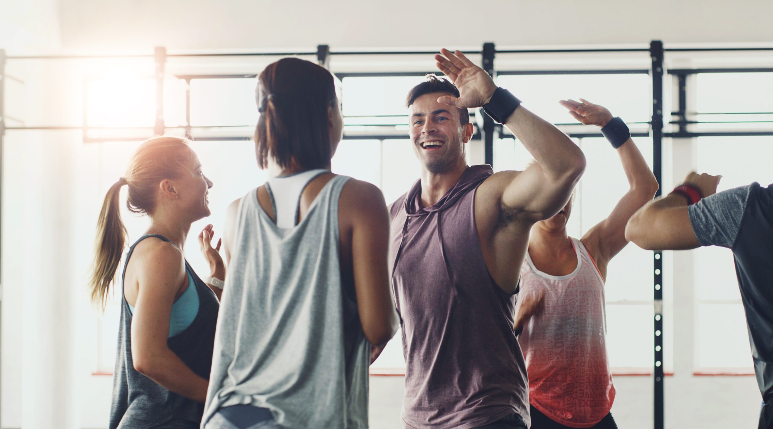 Group of people at the gym, encouraging one another with a smile and high-five.