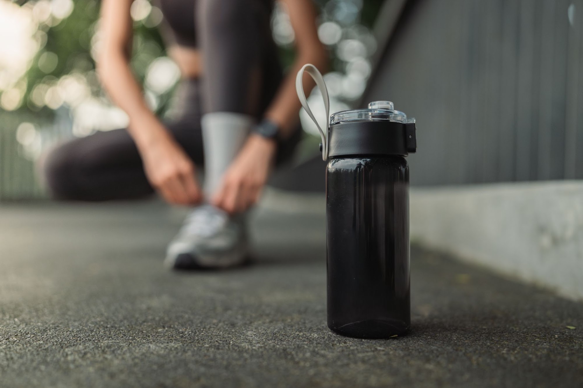 Reusable sports water bottle on the ground beside a training area