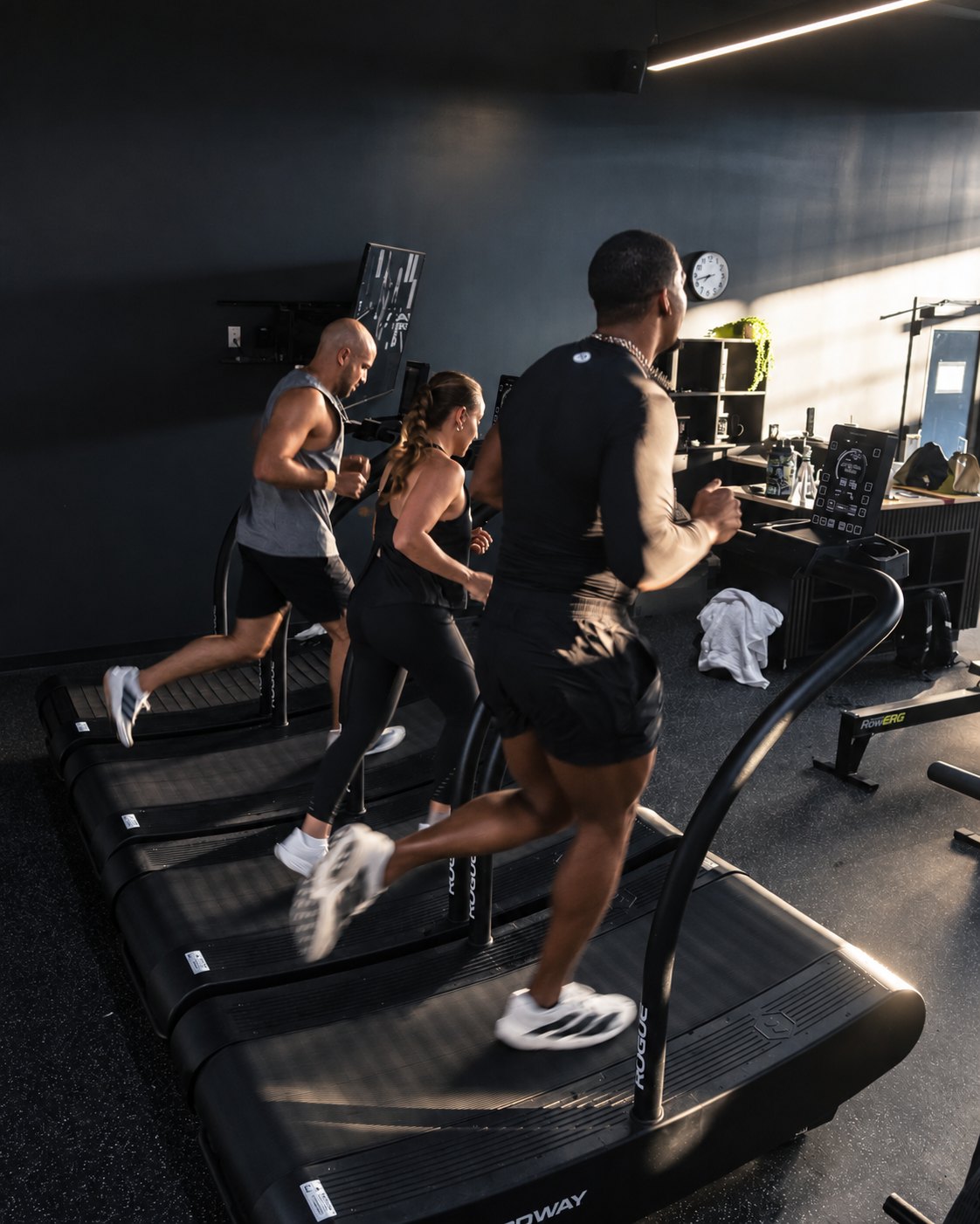 Members running side by side on curved treadmills