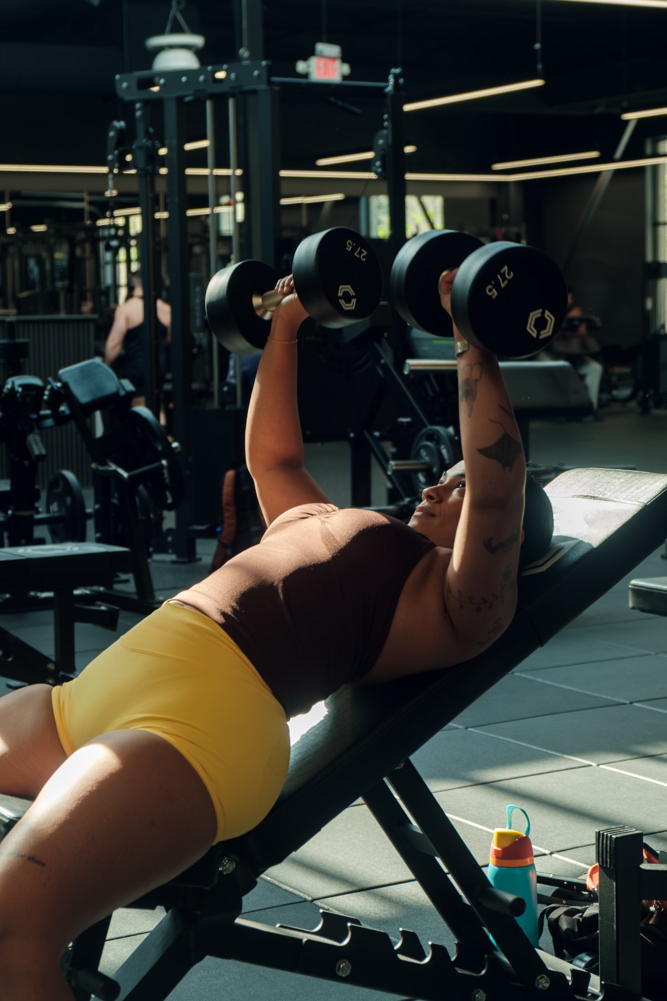 Member pressing dumbbells on an incline bench